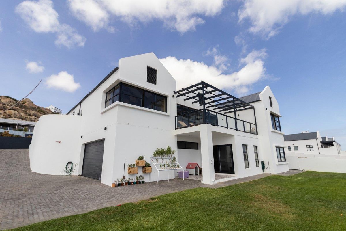 Modern two-story residence featuring a white facade, integrated garage, upper-level balcony with pergola, and a well-maintained lawn area.