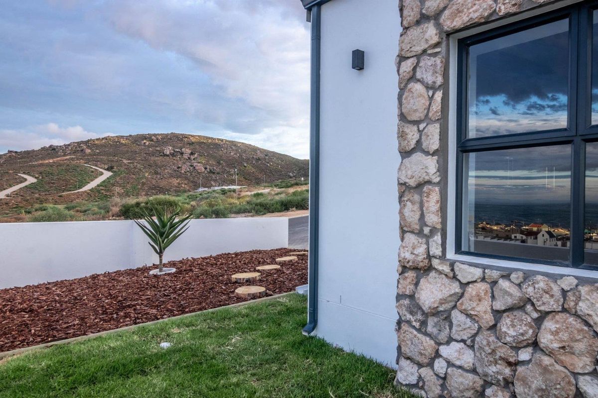 Exterior view of the property featuring stone cladding, a landscaped garden area with mulch, and scenic mountain views.