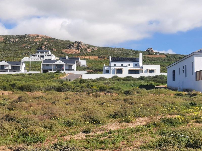 A scenic view of a residential estate featuring modern homes set against a natural hillside landscape.