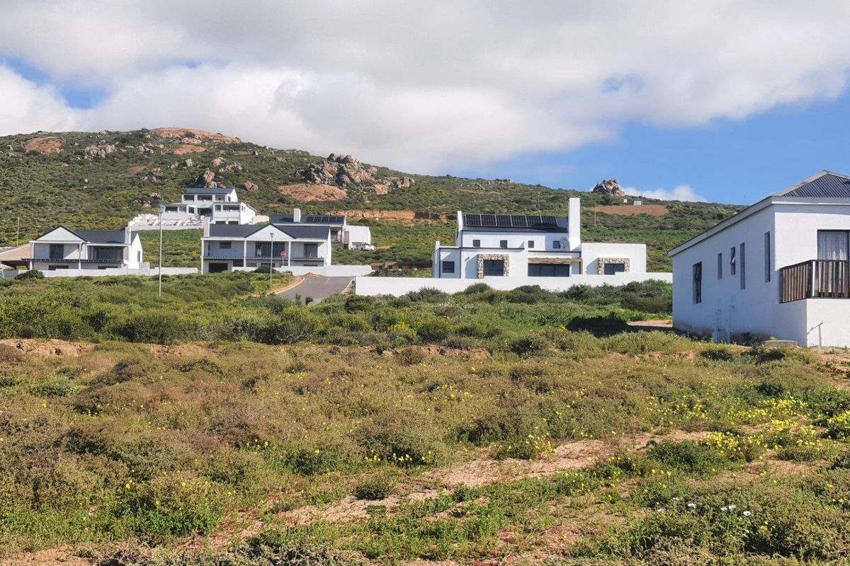 A scenic view of a residential estate featuring modern homes set against a natural hillside landscape.