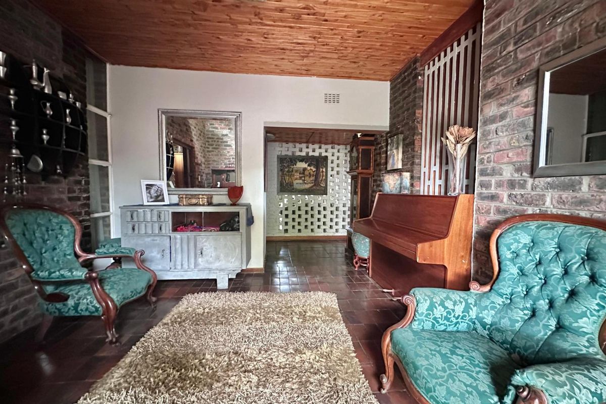 A living room featuring exposed brick walls, terracotta floor tiles, and a timber-clad ceiling, creating a rustic and traditional aesthetic.