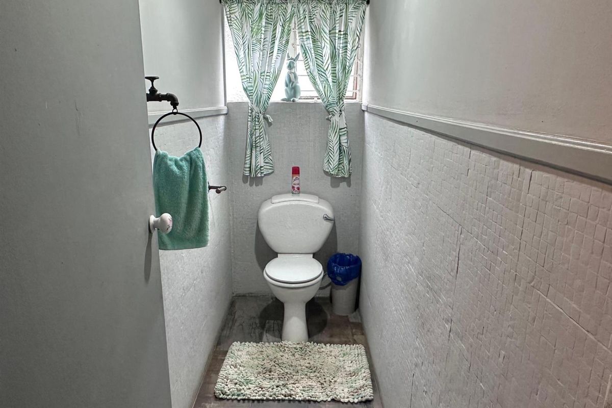 A compact guest toilet featuring a standard white ceramic toilet suite, tiled wall accents, and a small window with natural light.