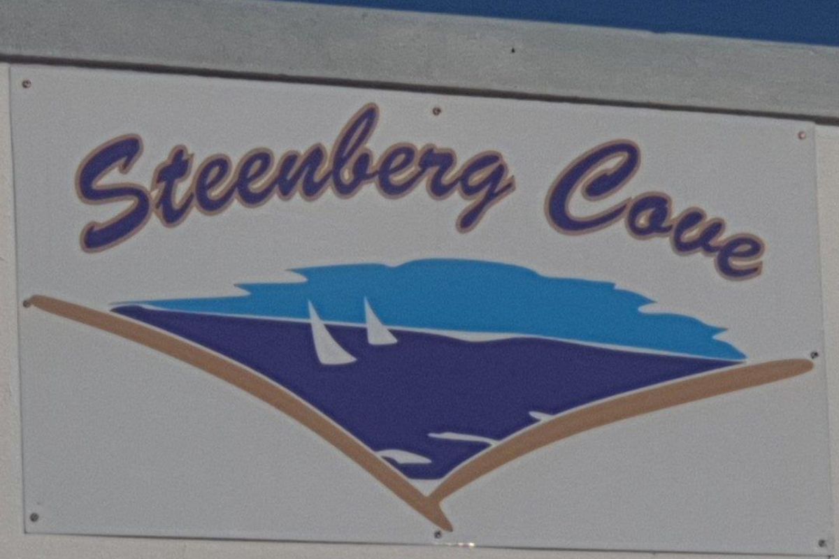A signage board displaying the name Steenberg Cove mounted on a wall.