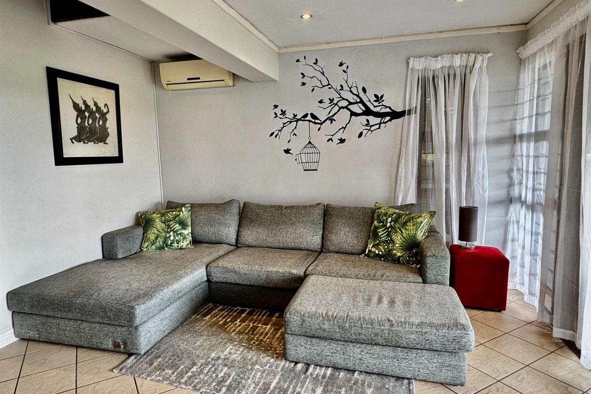 A comfortable living room featuring tiled flooring, recessed ceiling lighting, and a wall-mounted air conditioning unit.