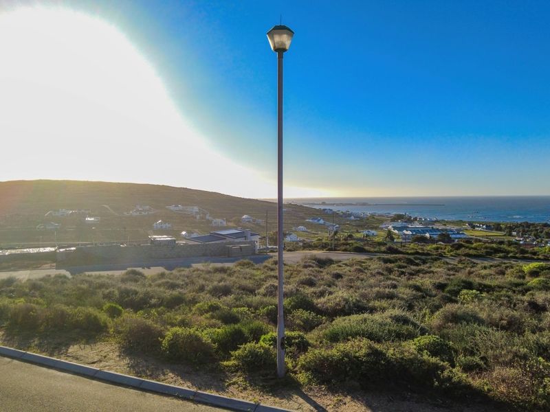 A scenic elevated view overlooking the coastal landscape and surrounding residential area, featuring natural vegetation and a clear horizon.