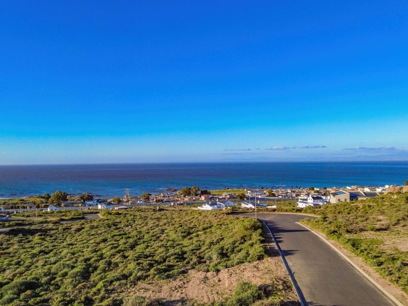 An aerial view of the vacant residential land, showcasing the surrounding coastal landscape, nearby neighborhood, and access road.