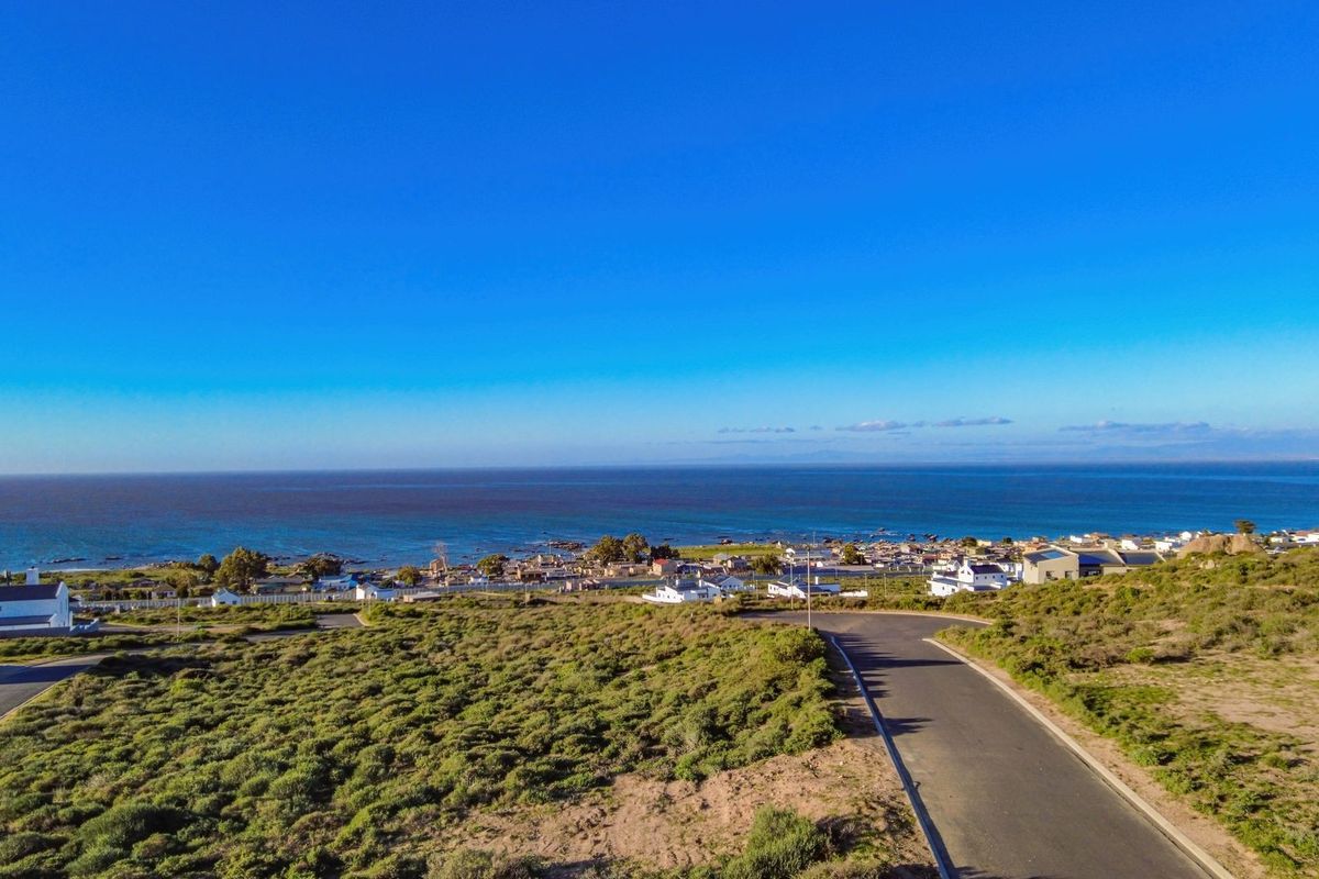 An aerial view of the vacant residential land, showcasing the surrounding coastal landscape, nearby neighborhood, and access road.