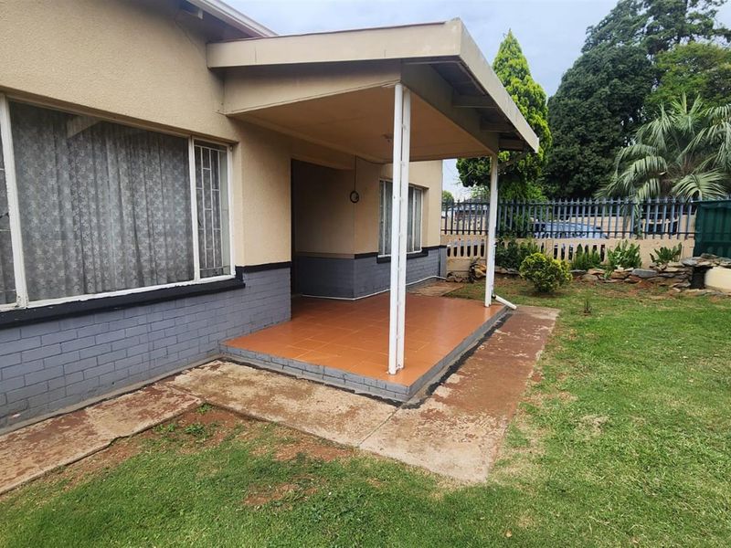 A covered patio area with tiled flooring, overlooking a private garden space with established lawn and perimeter fencing.