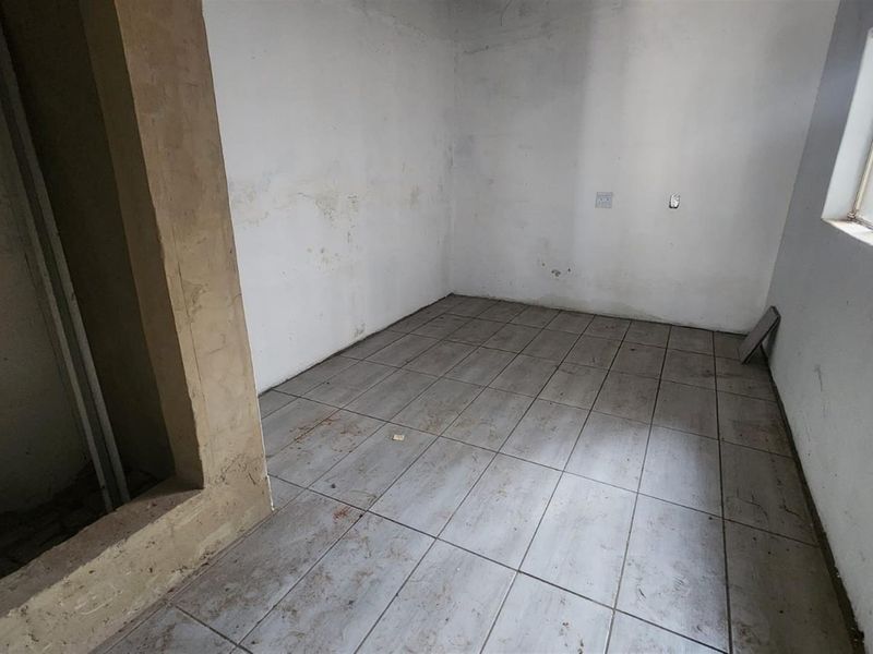 An empty, unfinished room featuring tiled flooring and plain walls, suitable for renovation or as a utility space.