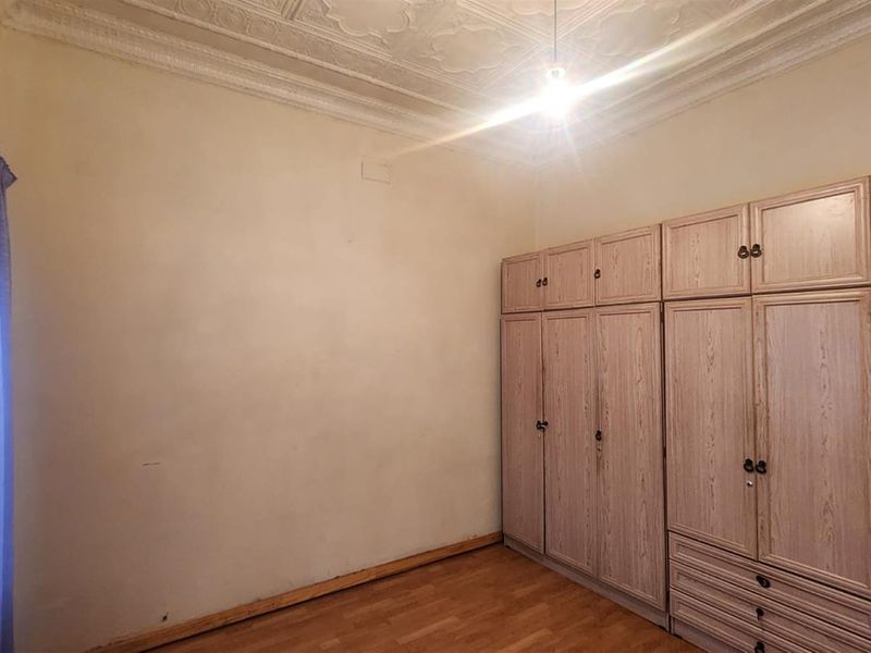 A bedroom featuring built-in wooden wardrobes, laminate flooring, and decorative ceiling molding.