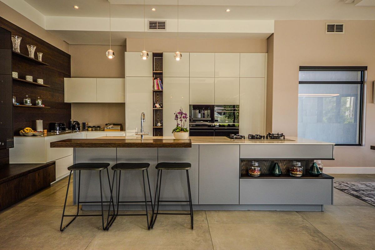 Modern kitchen featuring a large central island with breakfast bar, integrated cabinetry, built-in oven, and gas cooktop with sleek contemporary finishes.