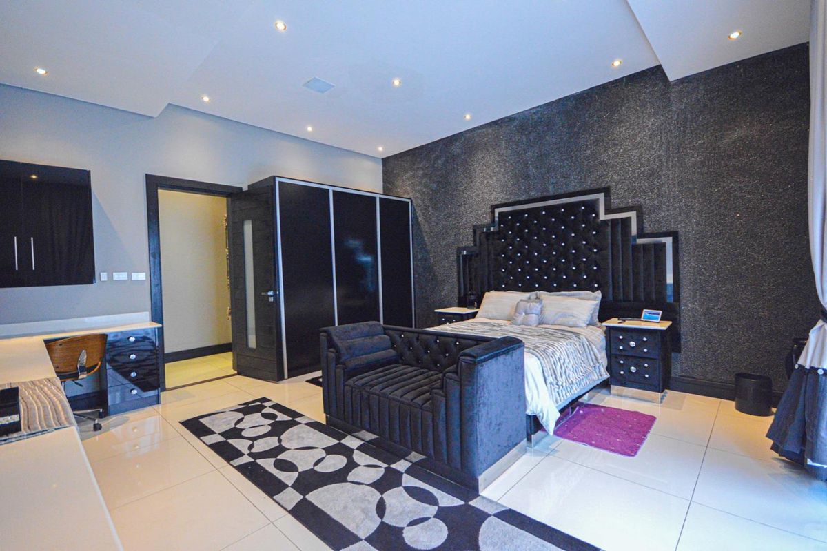 Spacious bedroom featuring built-in cabinetry, recessed ceiling lighting, and polished floor tiles, creating a modern and well-defined living space.