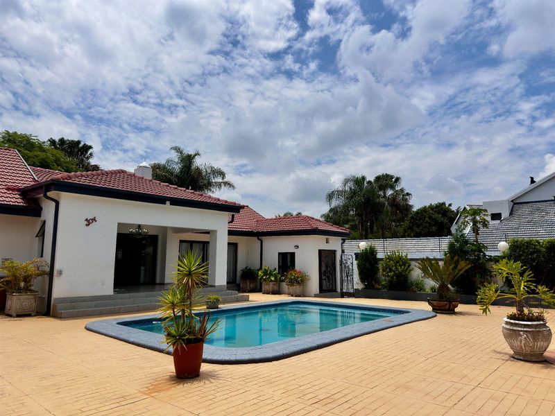 A well-maintained outdoor pool area featuring a paved patio, covered terrace, and terracotta roof tiles, ideal for outdoor relaxation and entertainment.