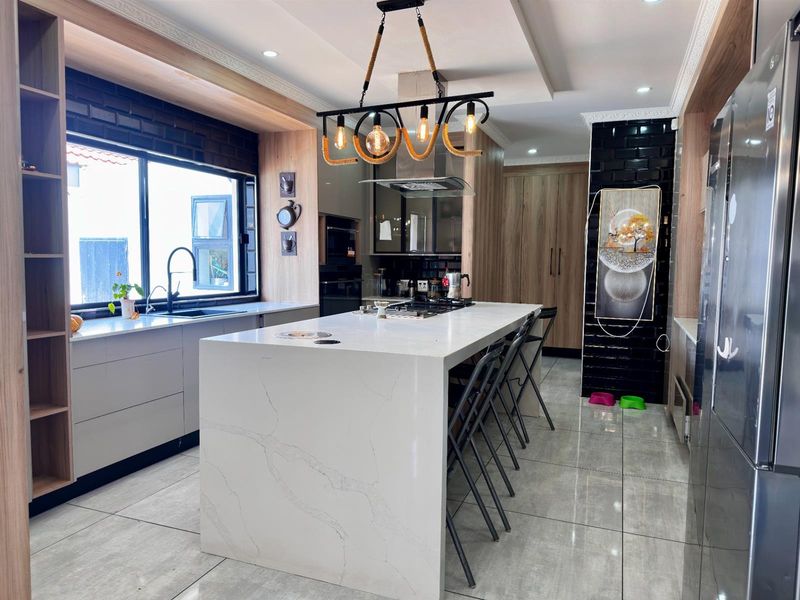 Modern kitchen featuring a large central island with stone countertops, integrated gas hob, sleek cabinetry, and high-end finishes throughout.