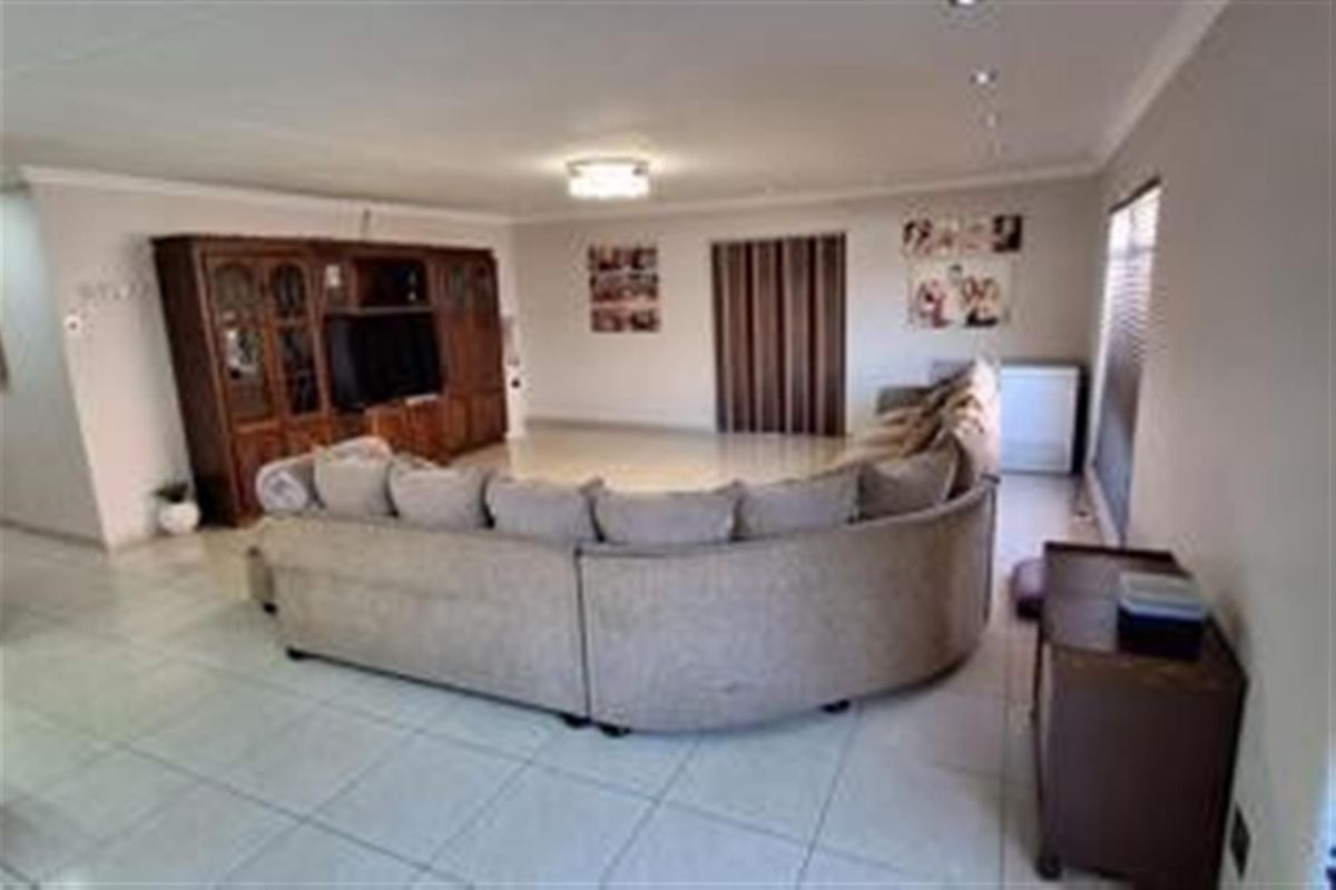 Spacious living room featuring tiled flooring, recessed downlighting, and a neutral color palette, providing a comfortable and versatile area for relaxation.