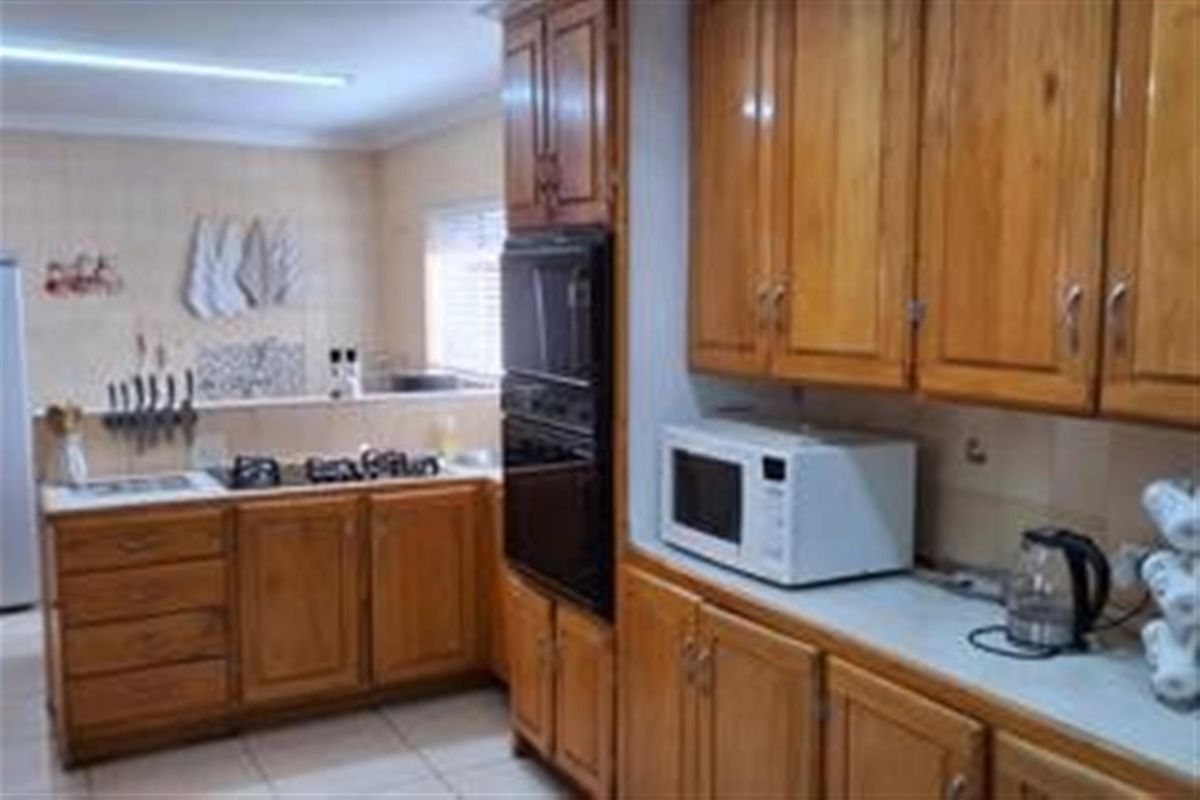 A functional kitchen featuring traditional timber cabinetry, built-in oven, and tiled splashbacks with ample counter space.