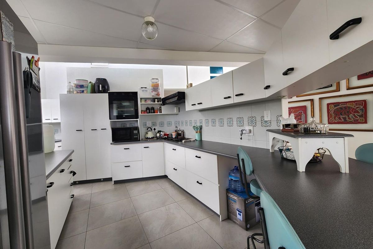 A functional kitchen featuring white cabinetry, dark countertops, tiled backsplash, and built-in oven, offering a clean and practical workspace.