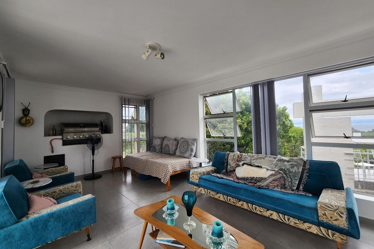 Spacious living area featuring large windows with natural light, tiled flooring, and a built-in indoor braai or fireplace.