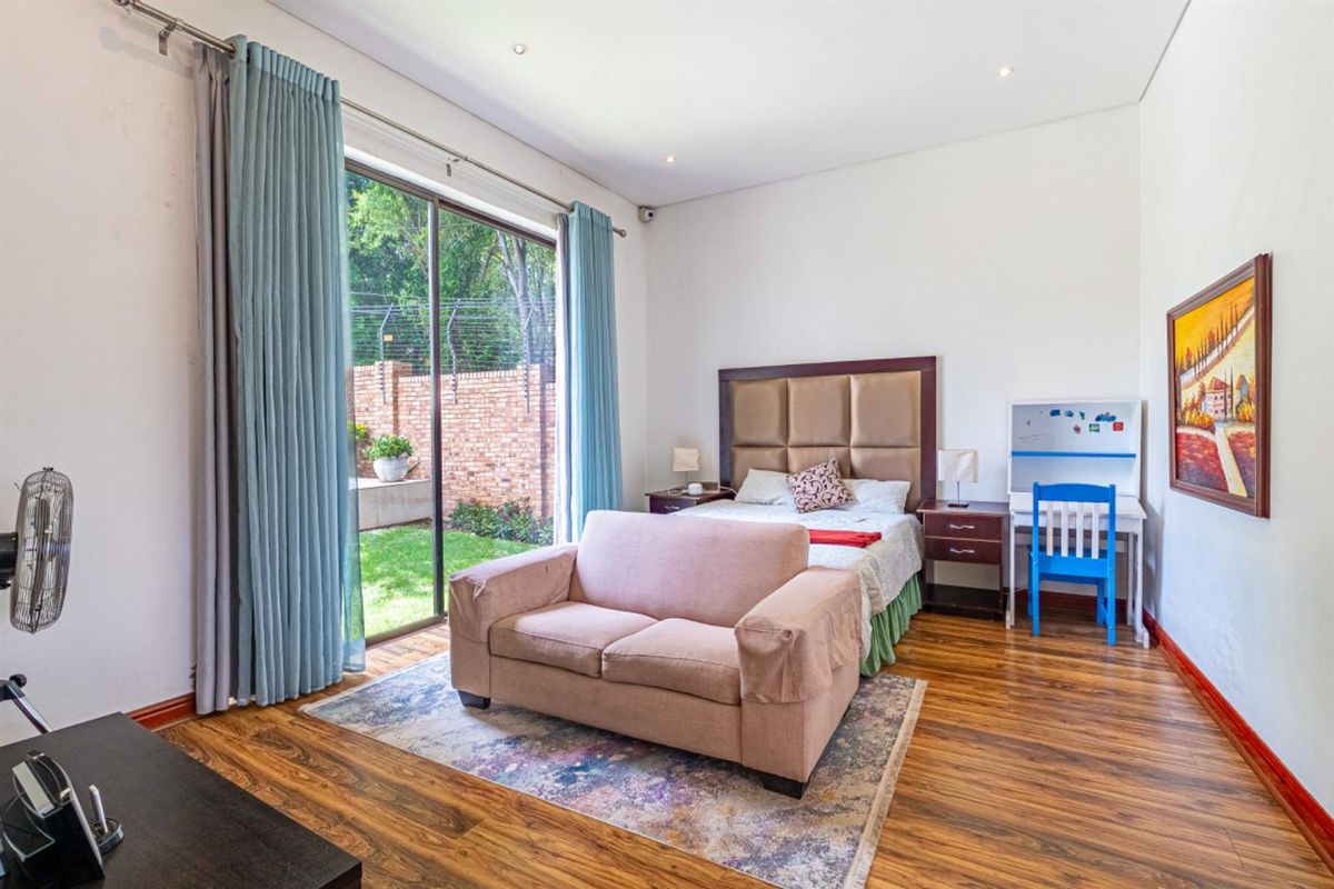 Spacious bedroom featuring wood-look flooring, recessed lighting, and large sliding glass doors providing direct access to the rear garden.
