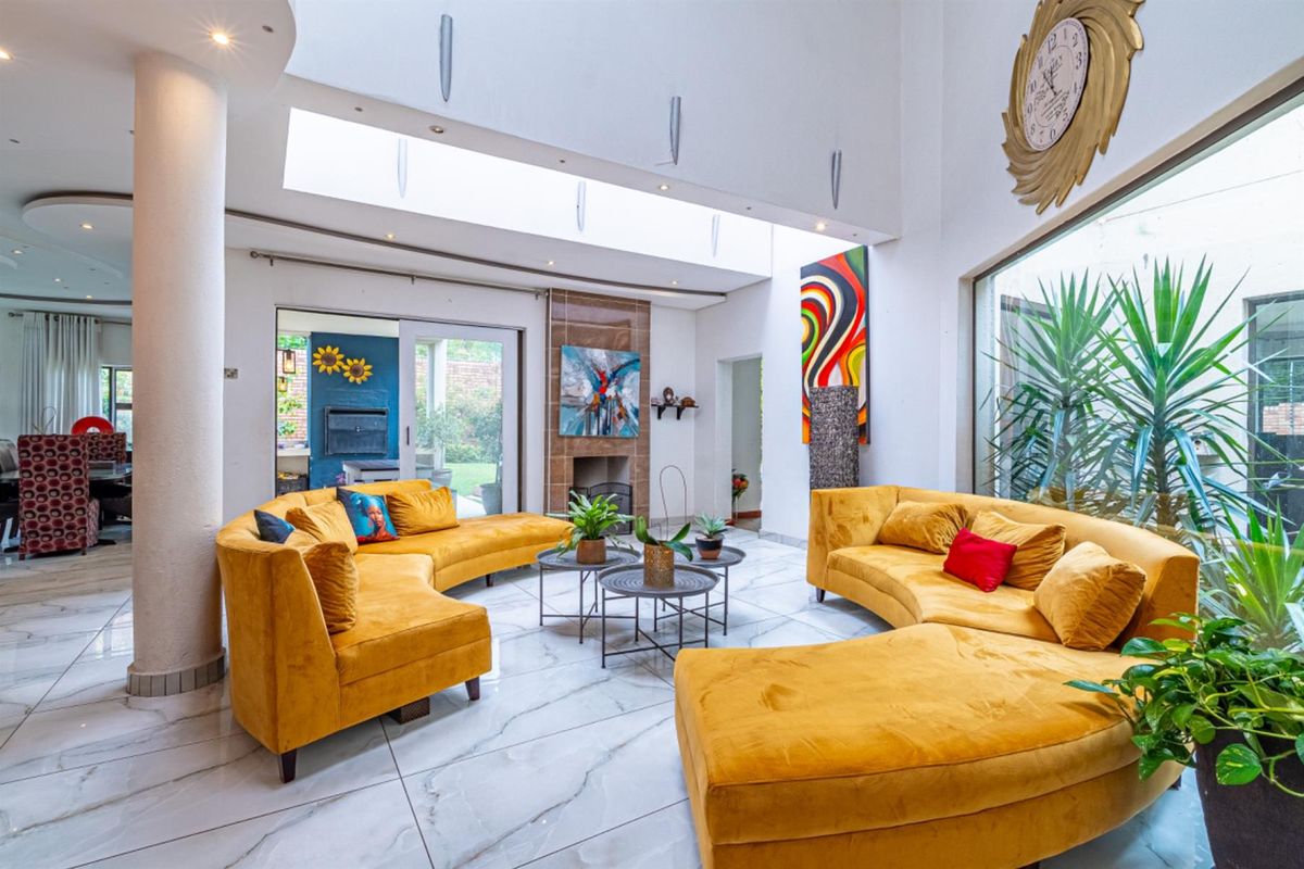 Spacious living area featuring high ceilings, large skylights, marble-style flooring, and a built-in fireplace, creating a bright and airy atmosphere.