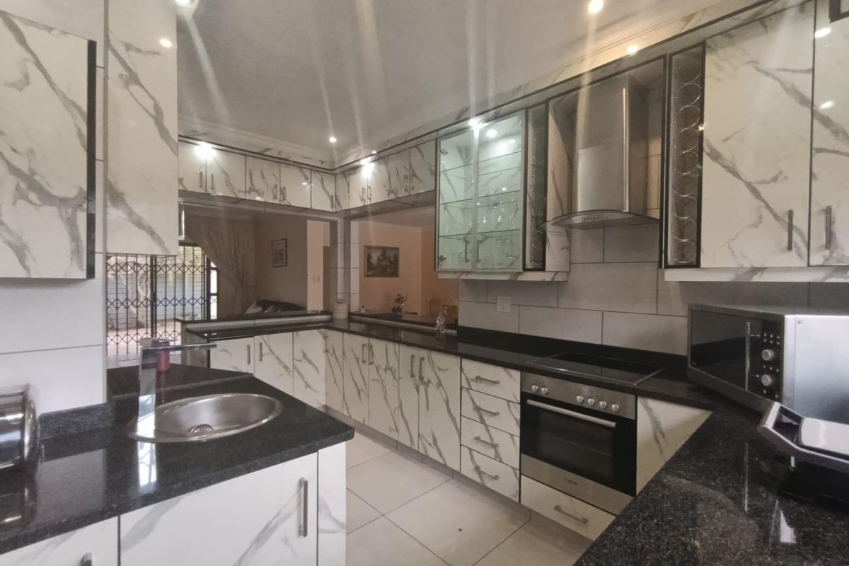 Modern kitchen featuring marble-effect cabinetry, granite countertops, integrated stainless steel appliances, and recessed lighting, offering a clean and functional workspace.