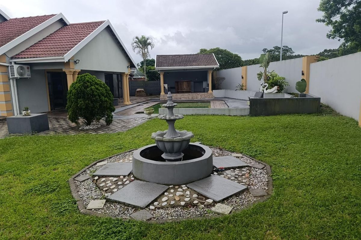 Spacious rear garden featuring a central stone fountain, a swimming pool, and a covered patio area, ideal for outdoor entertaining.