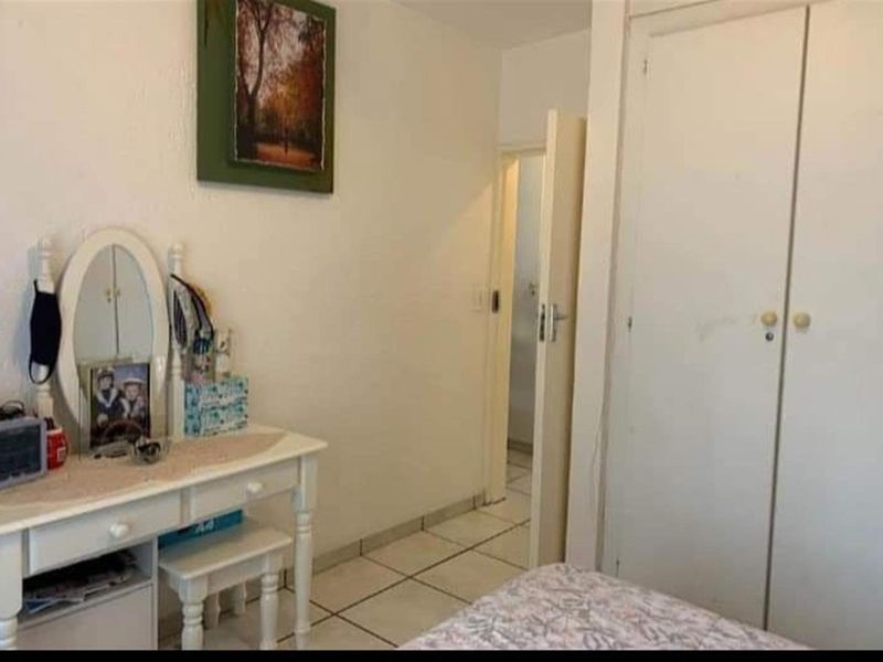 A functional bedroom featuring tiled flooring and built-in closet storage, providing a practical and neutral space.