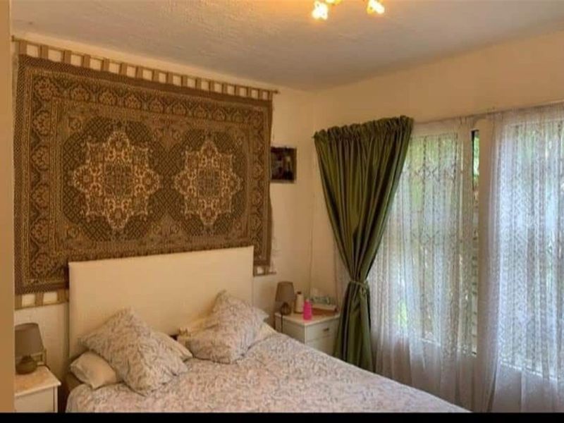 A bedroom featuring a window with curtains and a ceiling light fixture.
