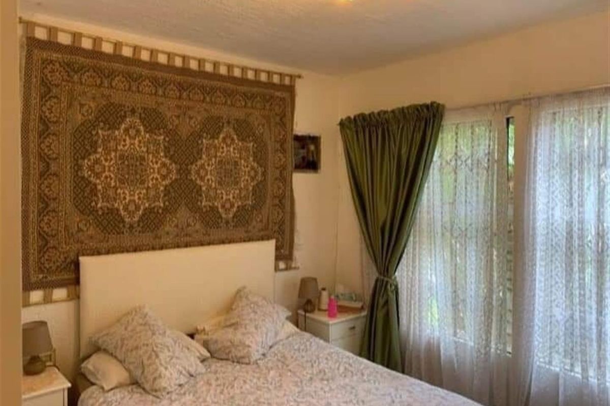 A bedroom featuring a window with curtains and a ceiling light fixture.