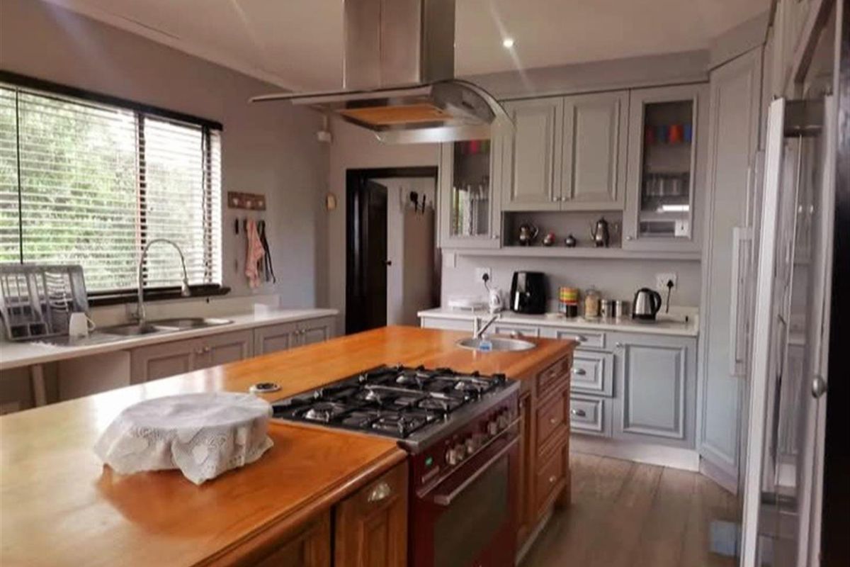 A well-appointed kitchen featuring a large wooden island with a built-in gas hob, stainless steel extractor fan, and classic grey cabinetry.