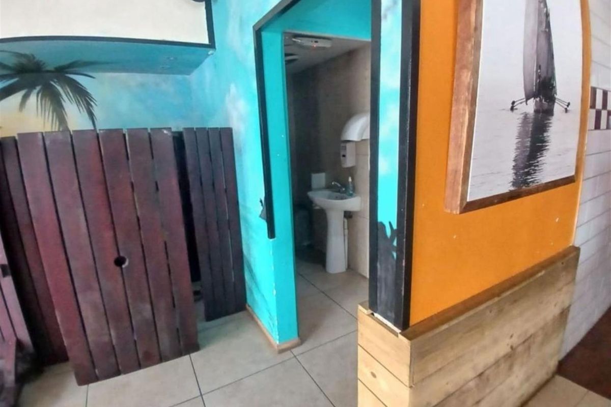 A view into a commercial restroom featuring a pedestal sink, tiled flooring, and decorative wall finishes.