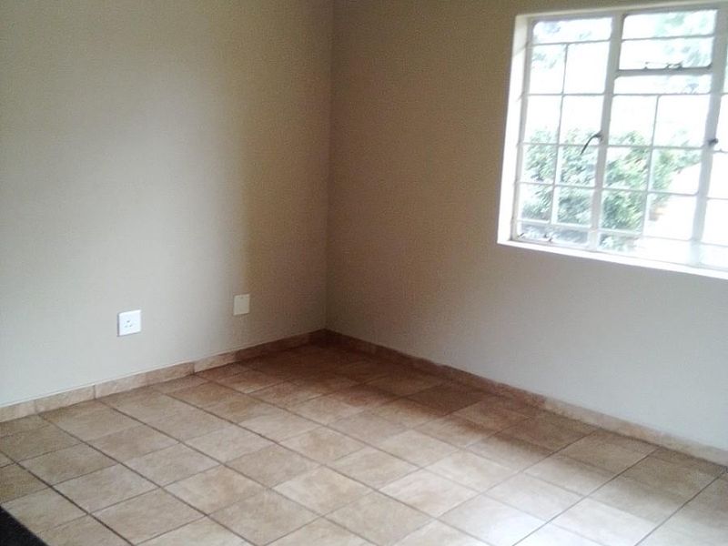 A clean, empty bedroom featuring neutral wall paint, tiled flooring, and a ceiling fan, providing a versatile space ready for personalization.