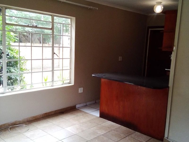 An open-plan living area featuring tiled flooring, a ceiling fan, and a breakfast bar, offering a functional space ready for modernization.