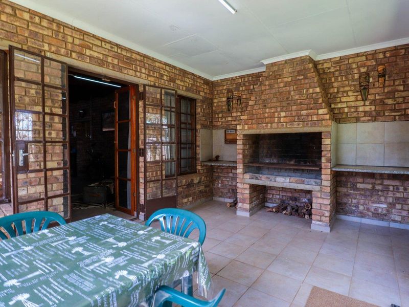 Covered outdoor patio featuring a built-in brick braai, tiled flooring, and direct access to the interior through large french doors.