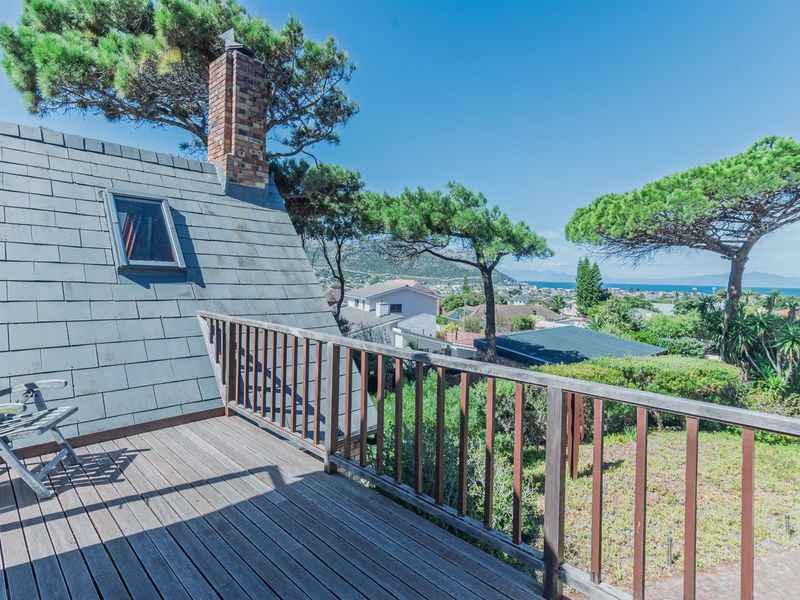 An elevated wooden balcony featuring a brick chimney and expansive coastal views, providing a scenic outdoor space for relaxation.