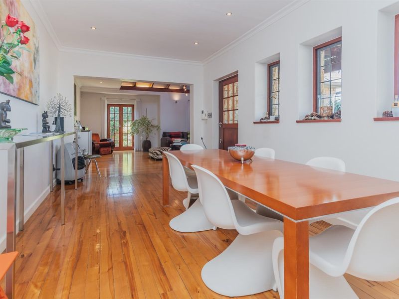 Open-plan dining area featuring polished timber flooring, recessed downlighting, and direct access to an adjoining living space through a wide transition.