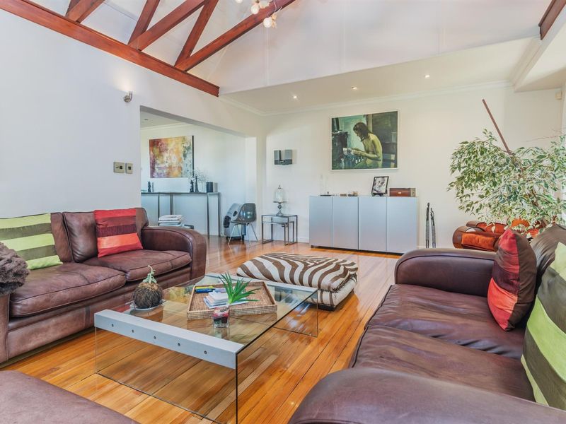 Spacious living area featuring high vaulted ceilings with exposed timber beams and polished hardwood flooring, creating a warm and inviting atmosphere.
