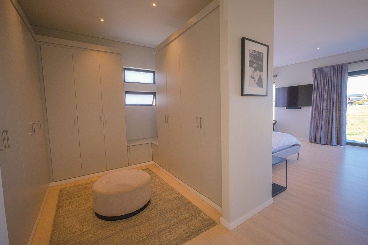 A modern bedroom featuring extensive built-in cabinetry, recessed ceiling lighting, and large sliding glass doors leading to an outdoor area.