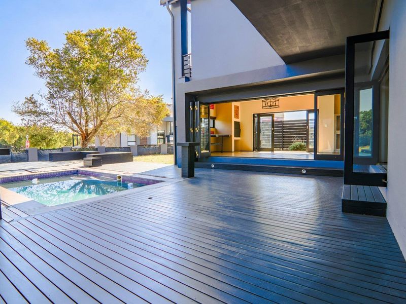 Spacious outdoor timber deck featuring a swimming pool and seamless indoor-outdoor flow through large bi-fold doors into the main living area.