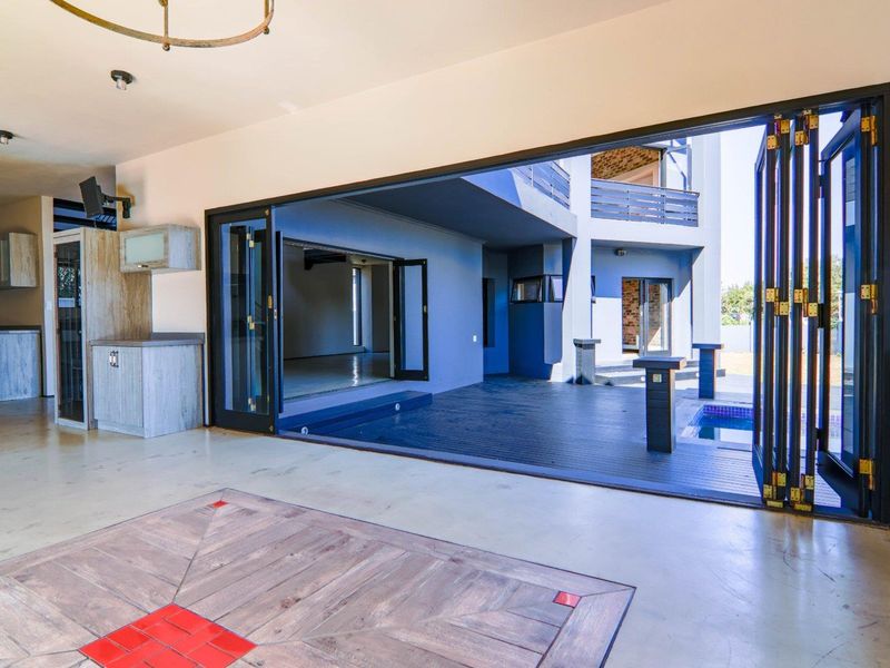 Spacious open-plan living area featuring large bi-fold doors that open onto a deck and swimming pool, creating a seamless indoor-outdoor flow.