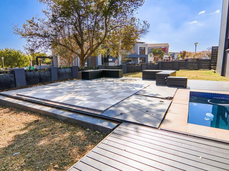 Outdoor pool area featuring a tiled patio, timber decking, and a swimming pool, set within a fenced garden space.