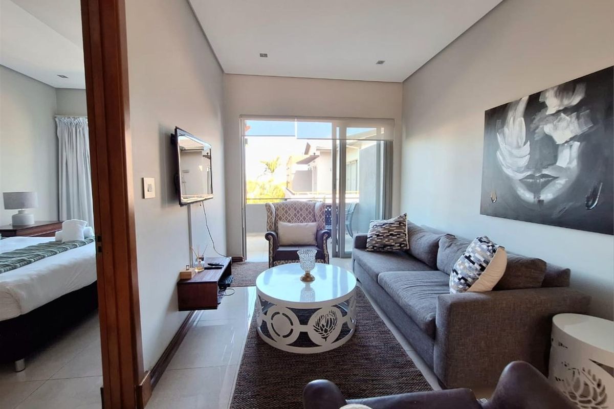 A bright living room featuring tiled flooring, recessed ceiling lighting, and sliding glass doors that open onto a private balcony.