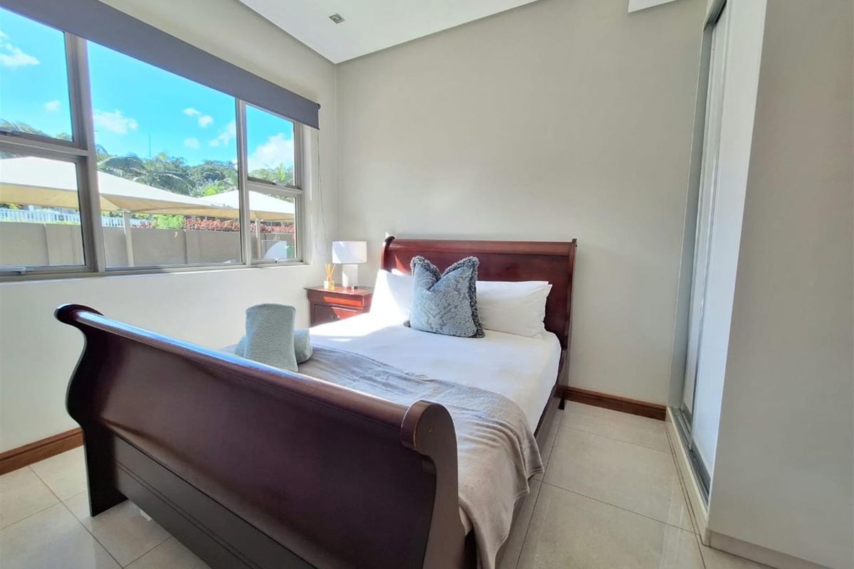 A bright bedroom featuring large windows, tiled flooring, and built-in sliding door cupboards.