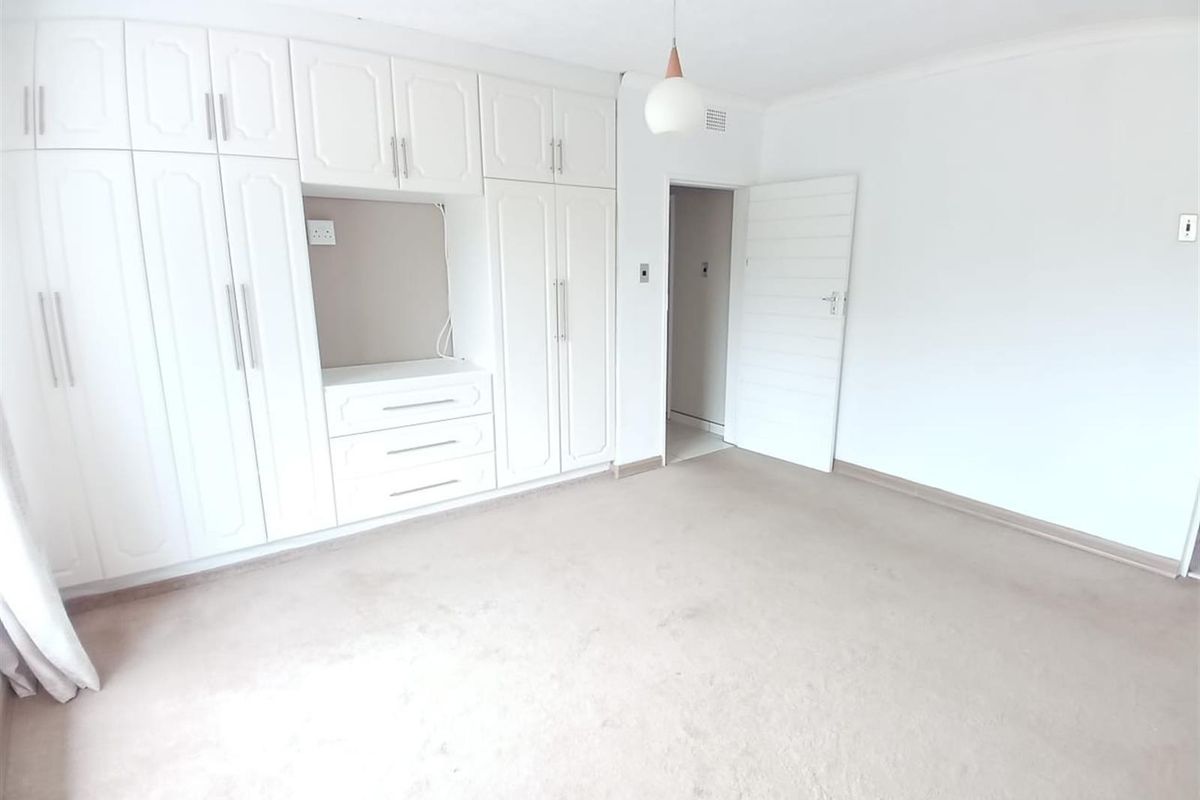 A bright bedroom featuring extensive built-in white cabinetry with integrated storage and neutral carpeting.