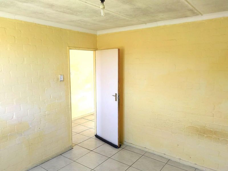 An empty room featuring tiled flooring and painted brick walls, showing signs of wear and requiring cosmetic updates.