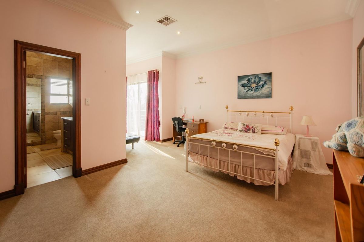 Spacious bedroom featuring neutral carpeting, recessed lighting, and direct access to an en-suite bathroom and a private balcony through sliding glass doors.