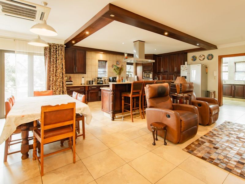 Spacious open-plan kitchen and dining area featuring dark wood cabinetry, a central island with breakfast bar, and neutral tiled flooring throughout.