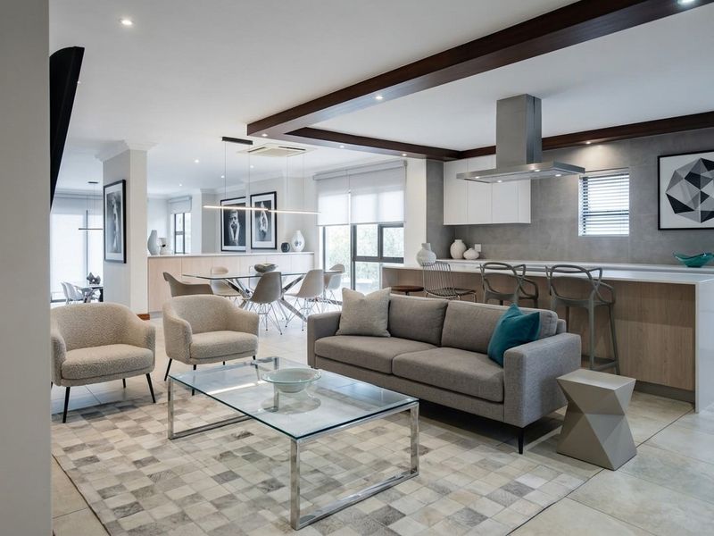 Modern open-plan living area featuring a sleek kitchen with a central island, exposed ceiling beams, and high-quality tiled flooring throughout the space.