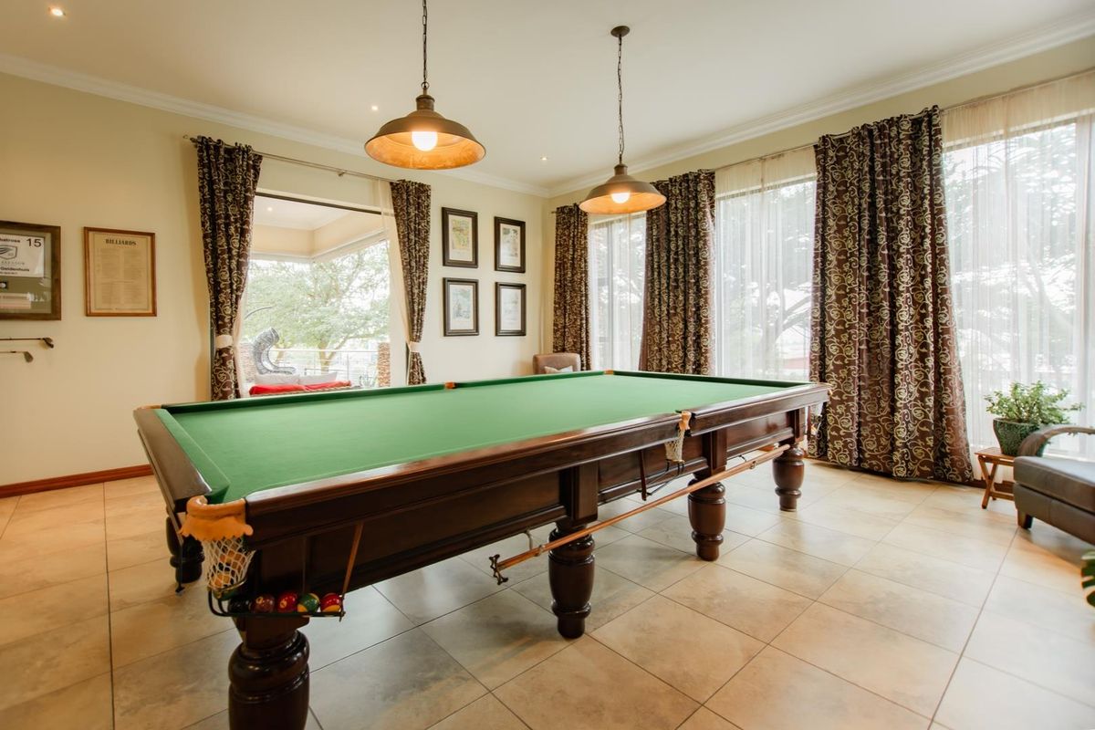 Spacious living area currently utilized as a games room, featuring tiled flooring, large windows with natural light, and direct access to an outdoor patio.