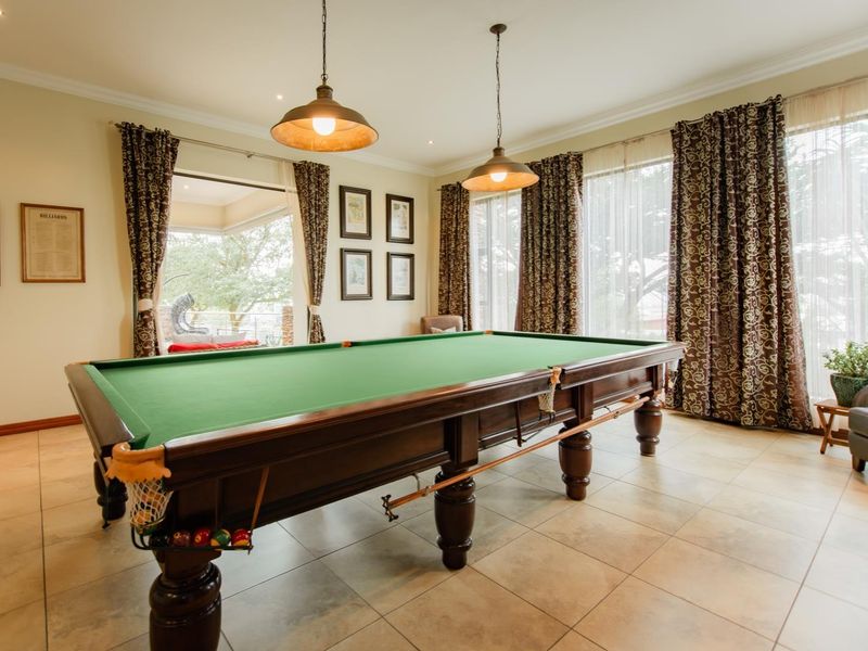 Spacious living area currently utilized as a games room, featuring tiled flooring, large windows with natural light, and direct access to an outdoor patio.